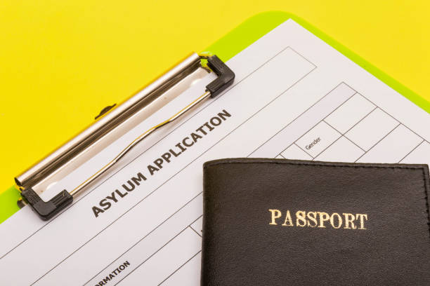 Asylum concept showing an application form for asylum on a yellow background with a passport